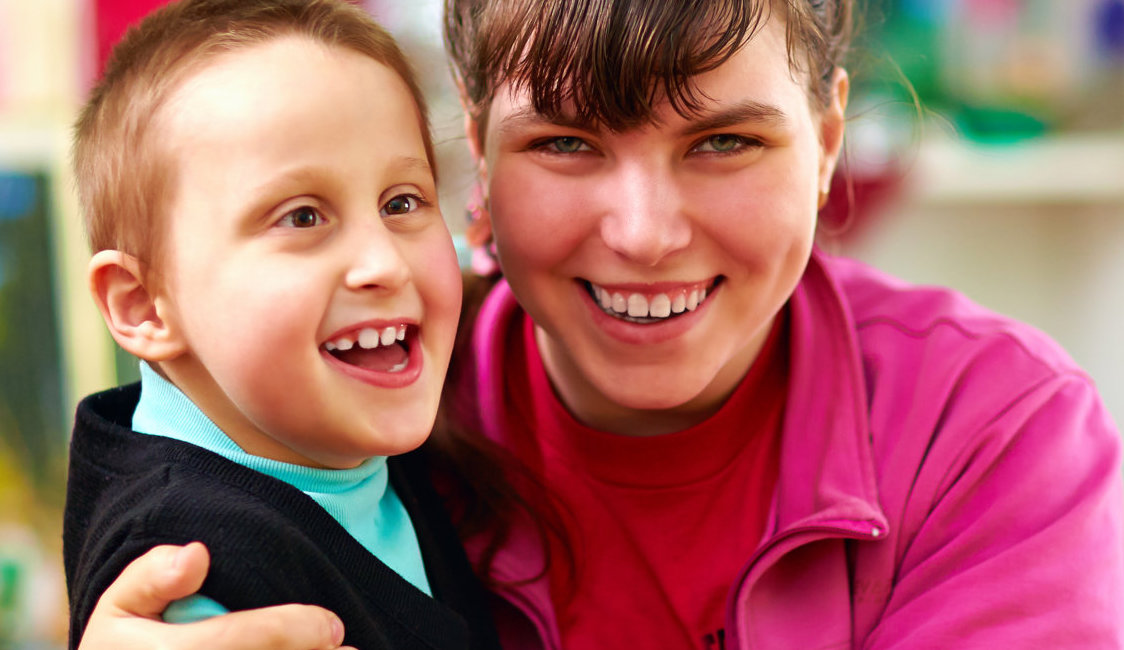 caretaker and a kid with disability smiling